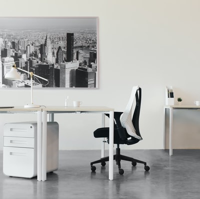 白色木质办公桌旁的黑白办公椅